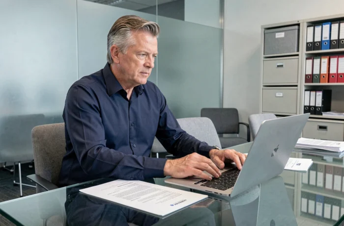 Homme téléchargeant Mon Proxima sur ordinateur portable pour la gestion administrative d'une tutelle